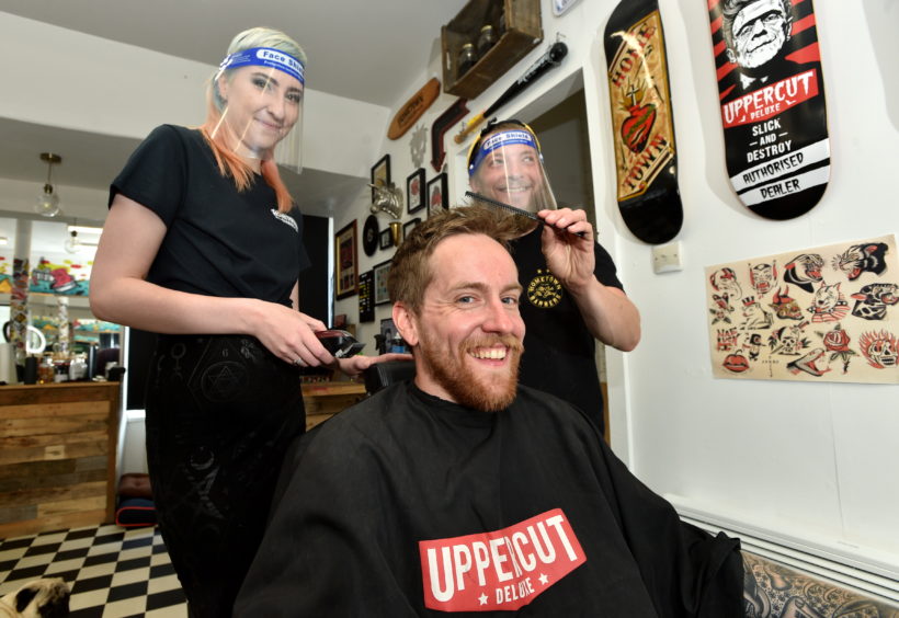 Laura Cowie, Roo MacKinnon and Mark Reilly celebrate the news at Hometown Barbers.