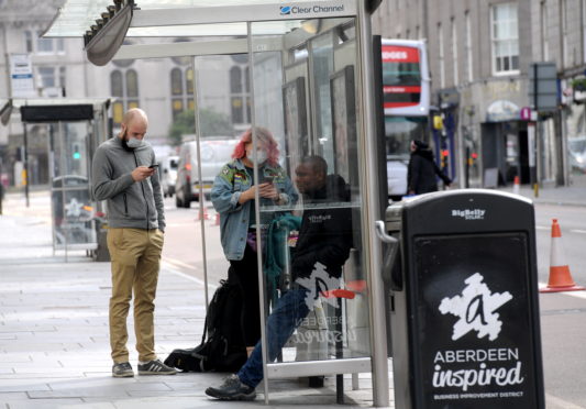 Passengers wear face coverings while waiting for a bus on Aberdeen's Union Street.