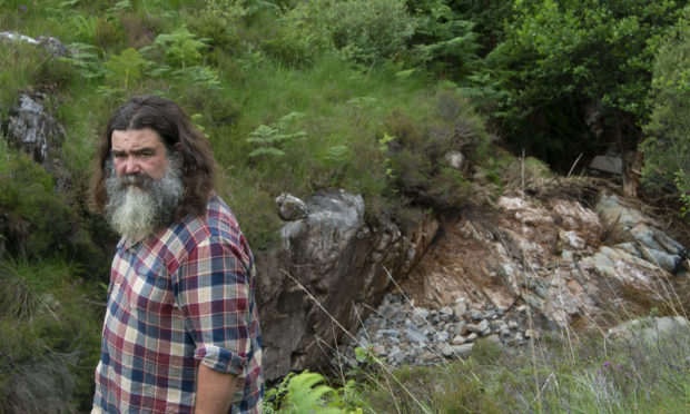 John Bryden beside the damaged caused by the flooding