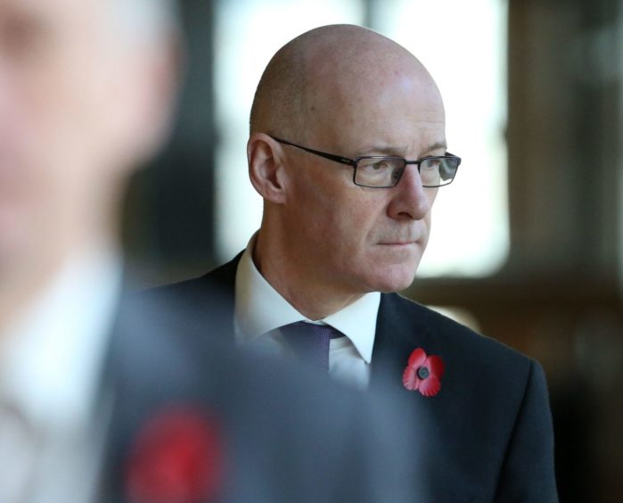 Education secretary John Swinney makes his way to the debating chamber to deliver his statement.