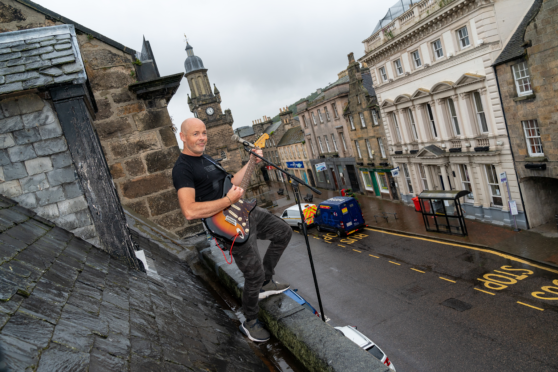 Dave Levon singing from his rooftop on High Street, Forres.