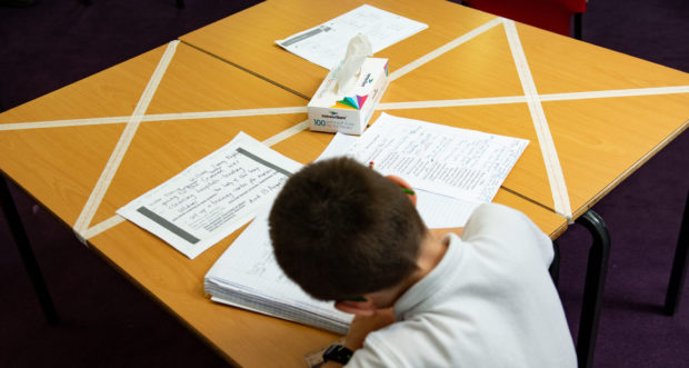 Schoolboy sitting at desk doing work.