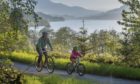 A family enjoying the stunning scenery along the banks of Loch Venachar on National Cycle Network Route 7. As part of the Aberfoyle-Callander and Lochs and Glens North portion of NCN 7, this stretch is notable for breathtaking views across the Loch and rolling mountain forests above.