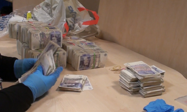 A National Crime Agency officer counts some of the confiscated cash.