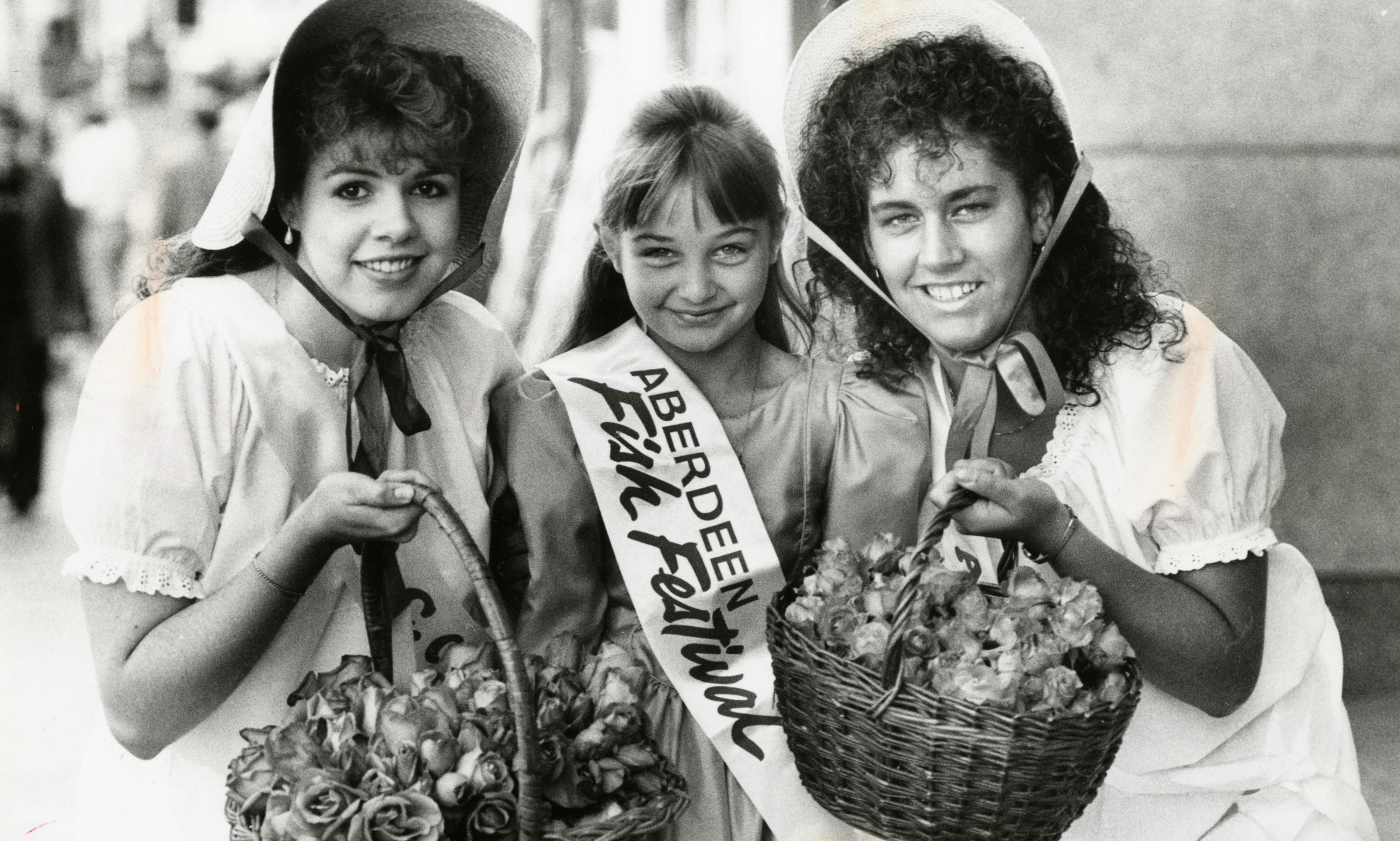 Young women wearing bonnets and carrying baskets of roses for the Aberdeen Rose Festival