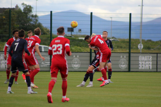 Dons defender Andrew Considine winning a header.