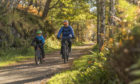A father and son cycling a country path, Ballater. The Cairngorms National Park