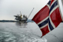A Norwegian national flag flies from the back of a boat in view of the the Aasta Hansteen gas platform.