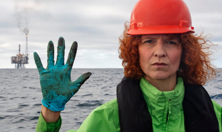 Greenpeace Germany Oceans campaigner Sandra Schoettner shows her gloves with the Andrew platform in the background