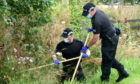Police search the verges and undergrowth close to the scene of the incident. Picture by Sandy McCook