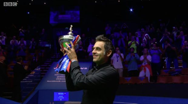 Ronnie O'Sullivan lifting the Betfred World Snooker Championship trophy.