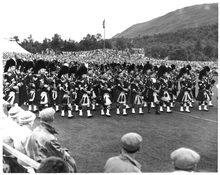 The massed pipe band march around the arena at the Braemar Highland Games.