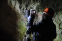 Archaeologists conducting Terrestrial Laser Scanning at the Sculptor's Cave in Moray.