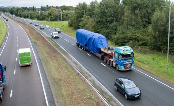 The locomotive being transported with a police escort on the A90.