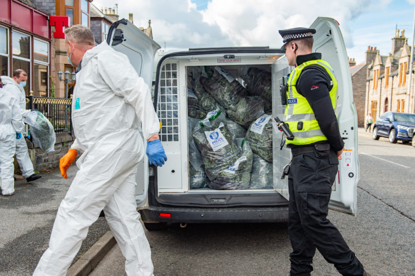 Police load a van outside the Highlander Hotel in Buckie.