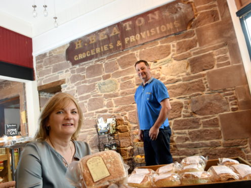 Owner Ann MacKinnon with her partner David Shields and the old shop sign they discovered. Picture by Sandy McCook.