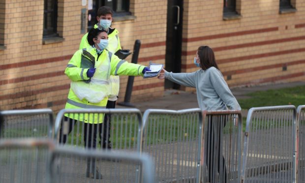 NHS staff hand out test kits to Glasgow University students as they arrive for testing at a pop up test centre