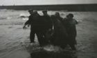 Rescuers bring a body ashore at Arbroath beach following the tragedy in 1953.