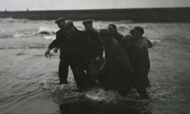 Rescuers bring a body ashore at Arbroath beach following the tragedy in 1953.