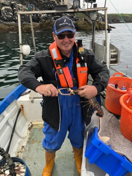 Mr Buchan, chief executive of the Scottish Seafood Association, on a boat holding a Scottish lobster.