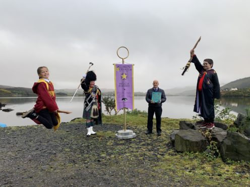 Eilidh Murray, Drum Major Peter MacDonald, councillor John Finlayson and Seamus MacDonald with the Quidditch banner.