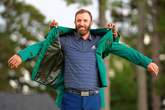 Tiger Woods helps Masters champion Dustin Johnson with his green jacket after his victory at the Masters golf tournament Sunday, Nov. 15, 2020, in Augusta, Ga. (AP Photo/Matt Slocum)