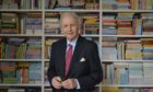Alexander McCall Smith has had an application to fit solar panels approved. He is standing in front of a library of books.