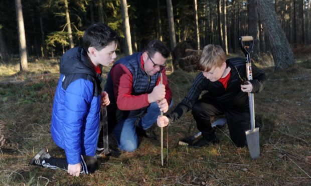 Angus Gardyne, 12, Steve Gardyne and Alasdair Lawson, 13, planting trees as part of their project to build a £140,000 skate park at Bell Wood, Aboyne