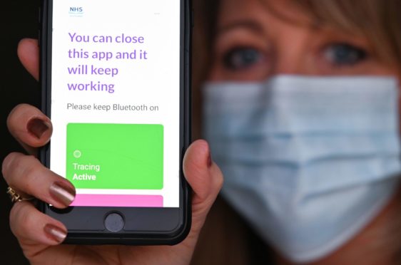 A member of the public views the new Covid-19 track and trace app on a phone at the Scottish Parliament in Edinburgh.