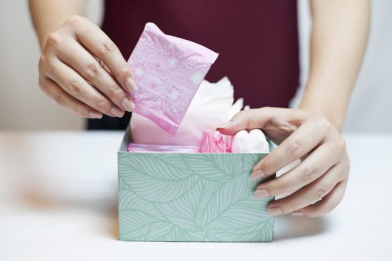 Closeup photo of young woman picking sanitary pad out of green box; Shutterstock ID 528070513; Purchase Order: My Weekly - December 19; Job: Dr Sarah Jarvis