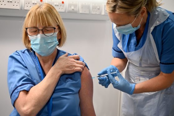 Grace Thomson (left) receives the first of two Pfizer/BioNTech Covid-19 vaccine jabs, administered Paula McMahon, at the NHS Louisa Jordan Hospital in Glasgow, on the first day of the largest immunisation programme in the UK's history.