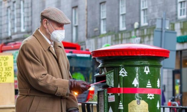 A man posts a card into the festive postbox on Union Street. Picture from Royal Mail