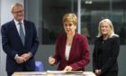 EMBARGOED TO 0001 MONDAY NOVEMBER 23 
Scotland's First Minister Nicola Sturgeon  flanked by  Scottish National Investment Bank CEO Eilidh Mactaggart and chair Willie Watt signs a visitors book at the bank's official launch at their headquarters in Edinburgh, Scotland. PA Photo. Picture date: Thursday November 19, 2020. Photo credit should read: Andy Buchanan/PA Wire