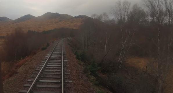 The train passing mountains on the approach to the Glenfinnan Viaduct.