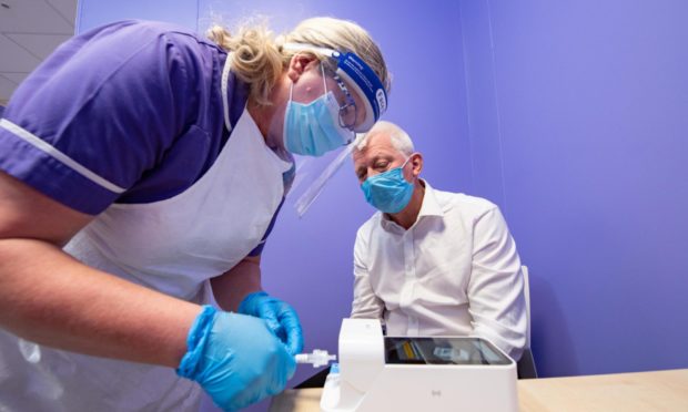 TAC Healthcare Group clinical director Ken Park looks on as a test for Covid-19 is carried out.