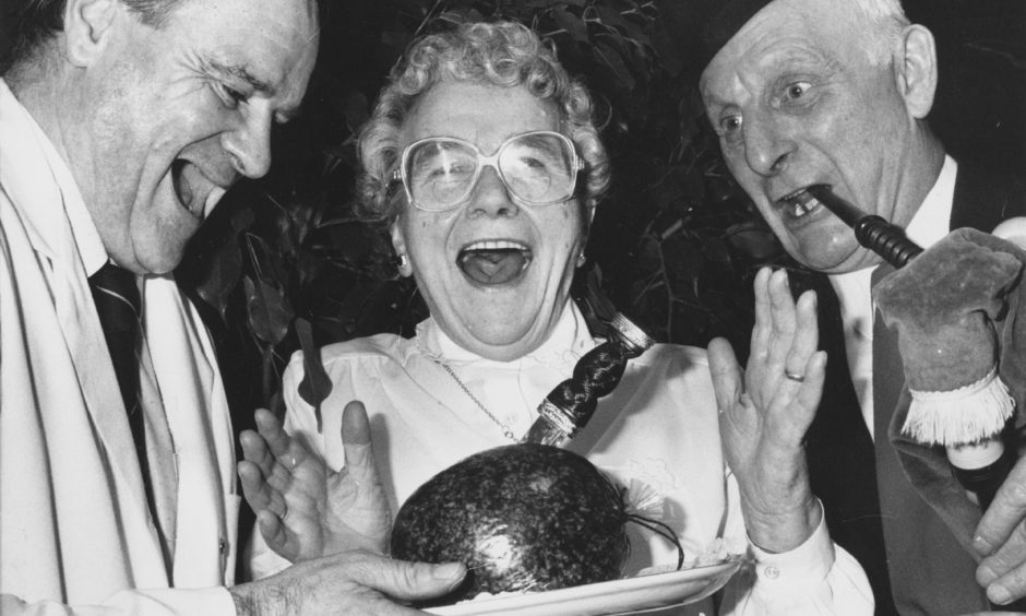 Tibby Main, one of the residents at Mark Bush Court, Kincorth, is obviously enjoying herself as she addresses the haggis at the court's Burns Supper in 1990. Aiding and abetting are chef John Wilson and piper Gordon Luke,