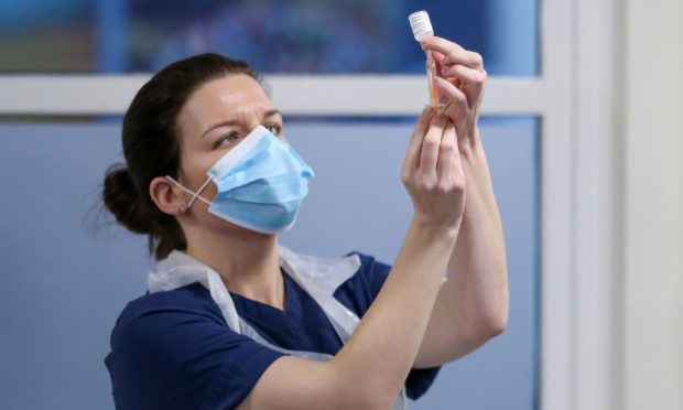 A healthcare worker fills a syringe with a dose of the Oxford/ AstraZeneca coronavirus vaccine in Edinburgh, Scotland, as the government continues to ramp up the vaccination programme.