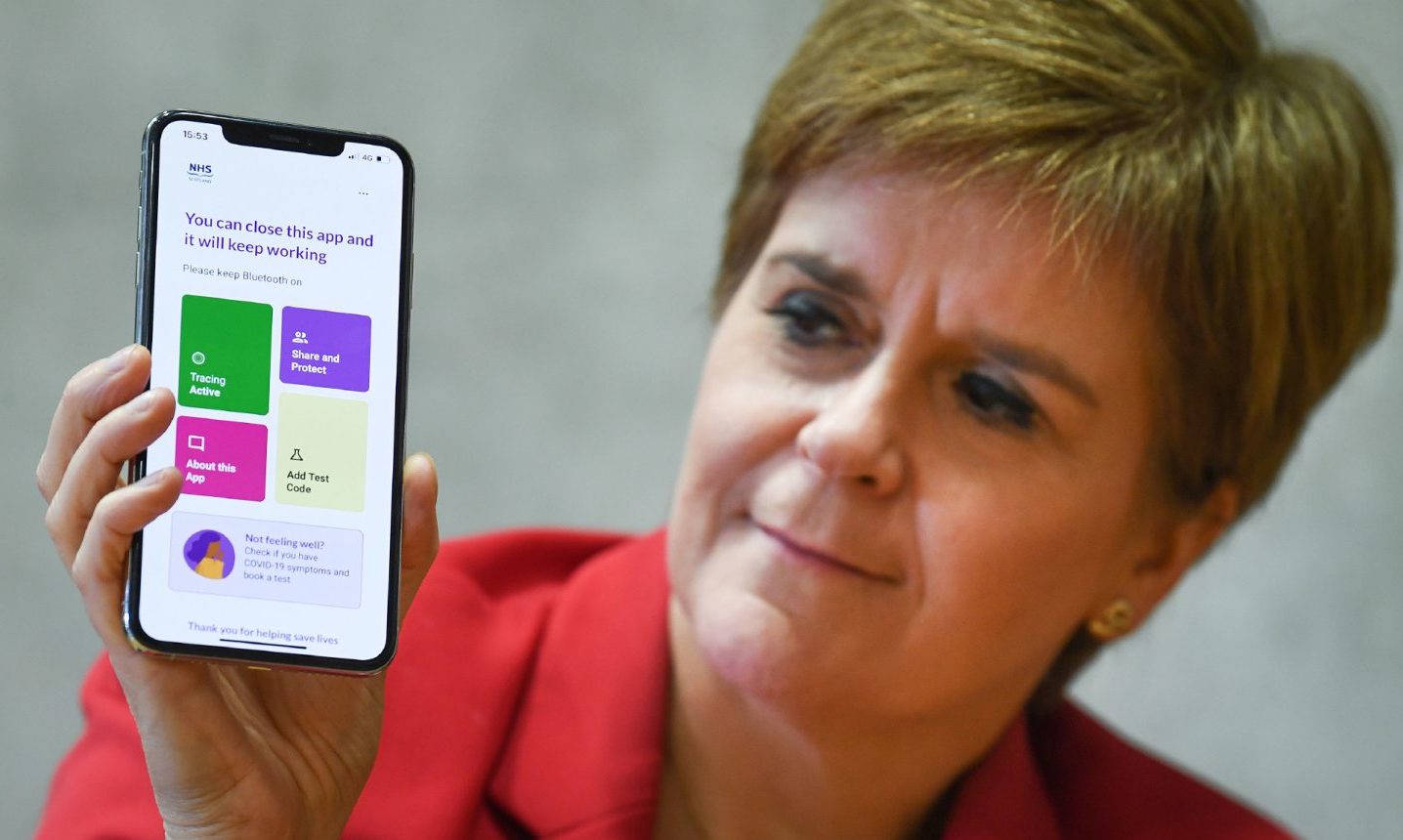 First Minister Nicola Sturgeon views the new Covid-19 track and trace app on a phone at the Scottish Parliament.