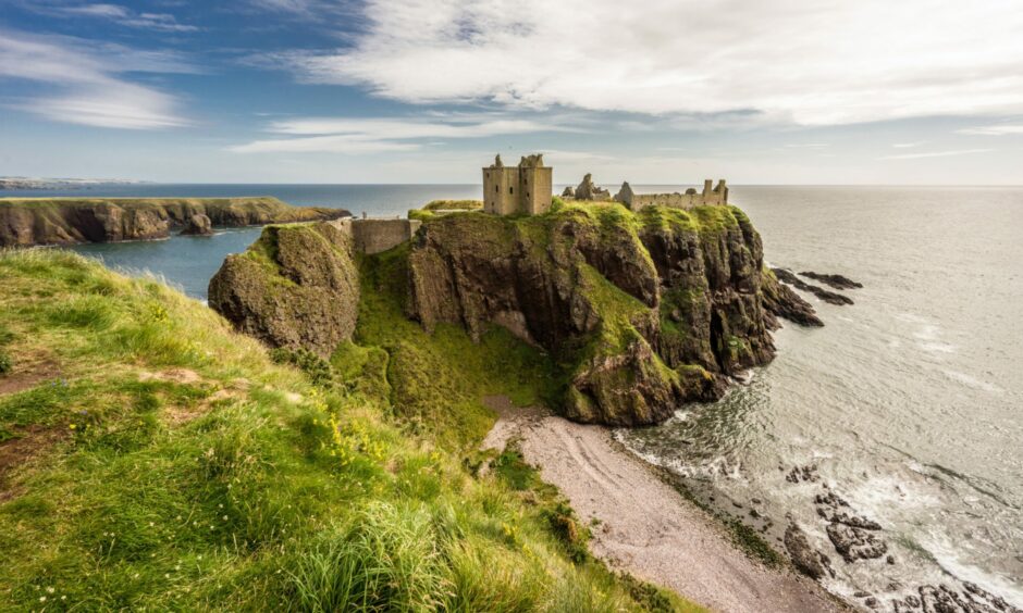 Dunnottar Castle from the distance with the beach and ruins in focus