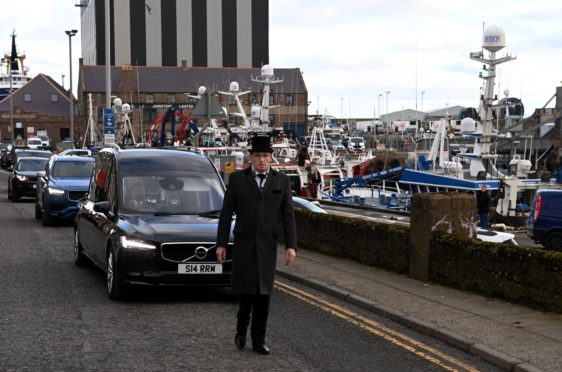 James West's funeral procession drives past some of the family's fishing boats at Peterhead Harbour. 

Picture by Kenny Elrick     02/02/2021