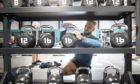 Gym member Brydon Smith cleans the weights after a workout at the new PureGym Local in Kirkcaldy, Fife.