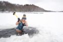 Alice Goodridge, from Newtonmore, uses a sledgehammer during a cold snap in 2021 to create a channel in the ice to swim in Loch Insh, in the Cairngorms National Park. Image: Jane Barlow/PA Wire.