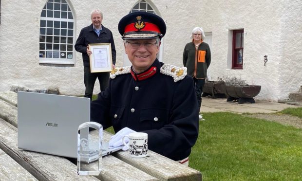 Lord Lieutenant of Banffshire, Andrew Simpson, presents the Queen's Award for Voluntary Service to Portsoy Community Enterprise chairman David Urquhart and director Anne McArthur at the Salmon Bothy.