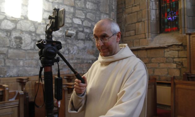 Brother Michael de Klerk sets up one of the cameras for livestreaming.