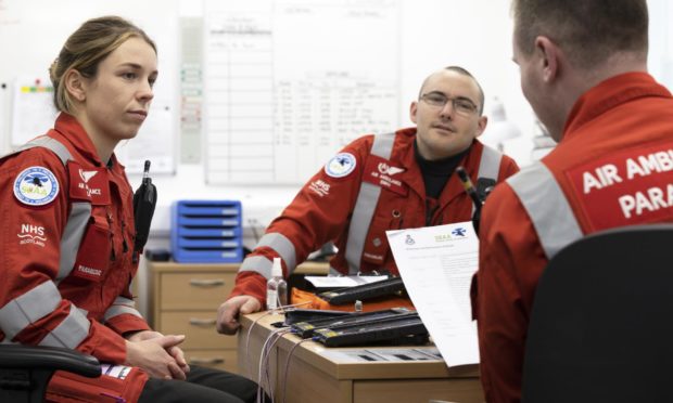 Scaa paramedics Laura McAllister, Ewan Littlejohn and Rich Forte discuss a brief at the charity's Aberdeen airport base