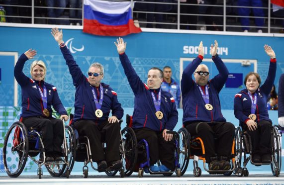 From left, Great Britain's Angie Malone, Jim Gault, Bob McPherson, Gregor Ewan, and Aileen Neilson celebrate after wining bronze medals after the wheelchair curling match between Great Britain and China at the 2014 Winter Paralympics in Sochi, Russia.