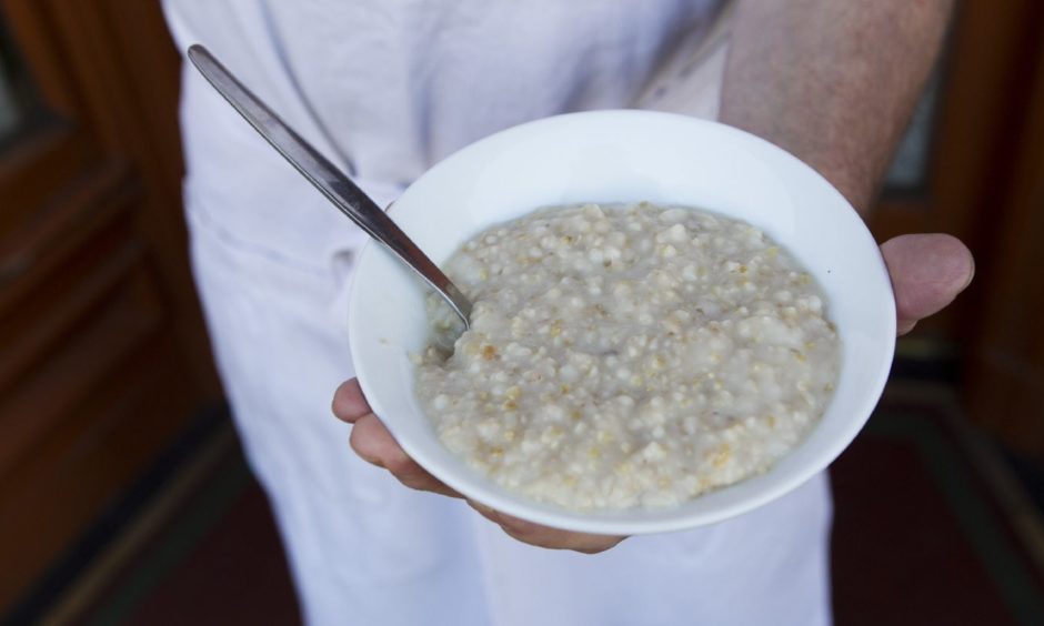 A hand holding a bowl of porridge