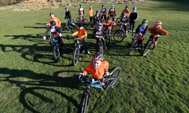 Pictured is Rory Nicholson, 7, with members of the Grampain Tigers Youth Cycling club behind him.