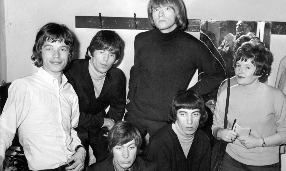 The Rolling Stones - Mick Jagger, Keith Richard, Charlie Watts, Brian Jones, and Bill Wyman - with reporter Julie Davidson before their gig at the Capitol in 1965.