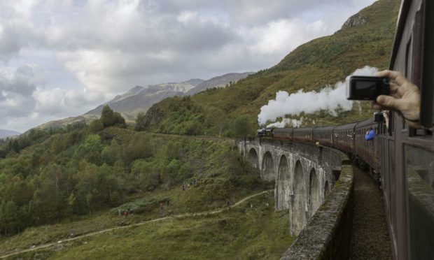 The steam train crosses Glenfinnan viaduct.